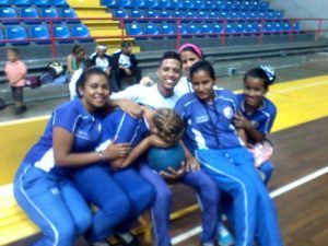 Integrantes del equipo femenino del Zulia en un banco en el gimnasio sede del evento.