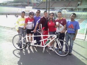 Rafael Rodríguez, Edgar Ugas, Luis Miguel Orozco, Kelvin Medina, y John Gary Donoso, de los Caimanes de Bolívar Goalball Club, con la bicicleta tándem, y Valentina García, atleta con discapacidad visual, practicante de esa disciplina, junto a su guía vidente, conductora de la bicicleta.